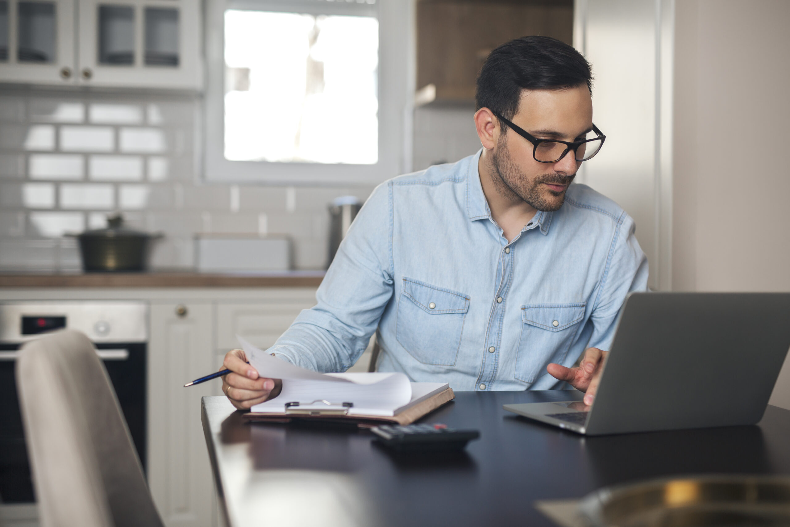 Young man doing paperwork from home.