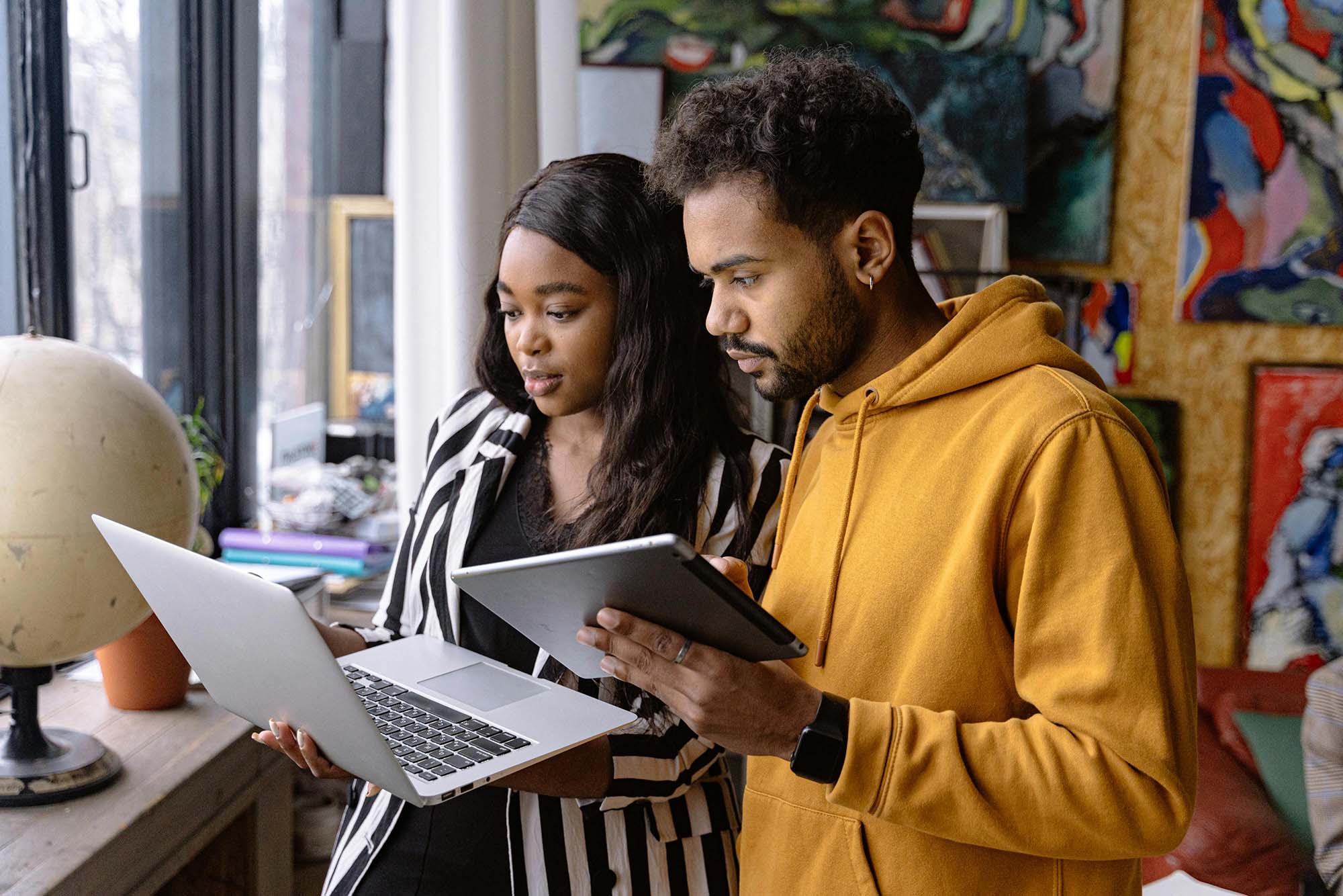 Two coworkers collaborating on financial close reconciliation tasks with laptop and tablet
